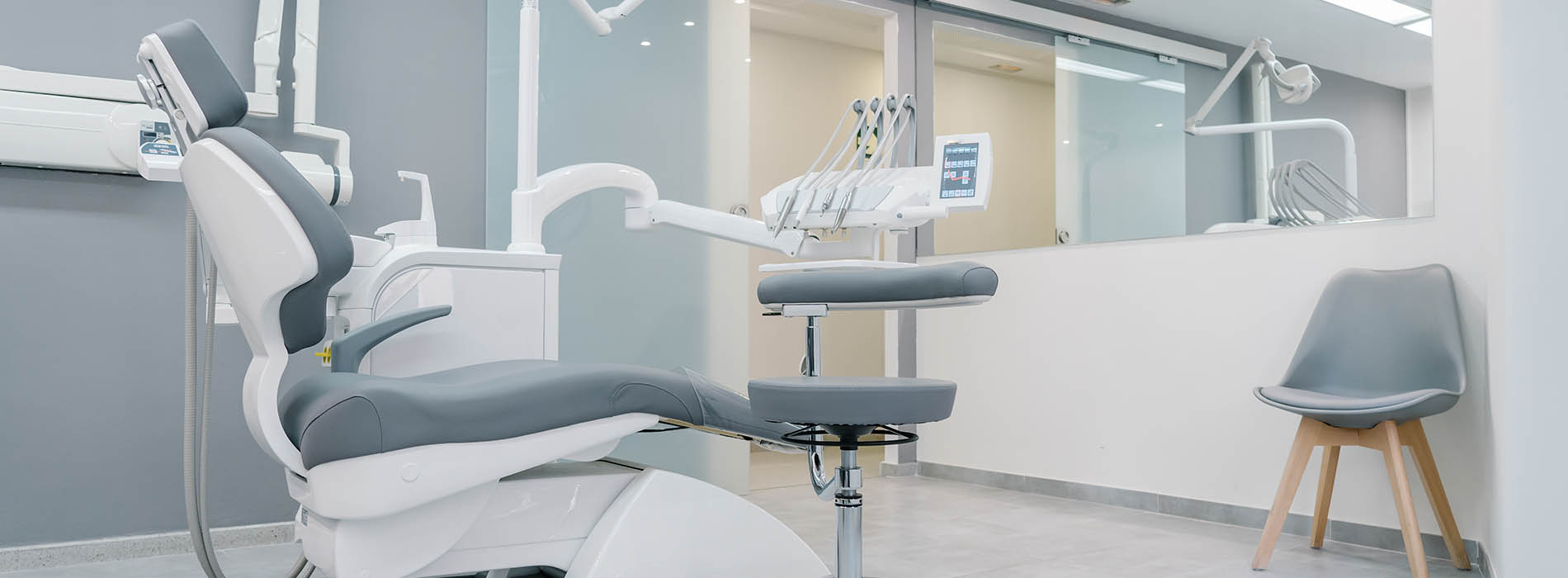 The image shows a modern dental office interior with dental chairs, equipment, and a reception area featuring a desk and seating.