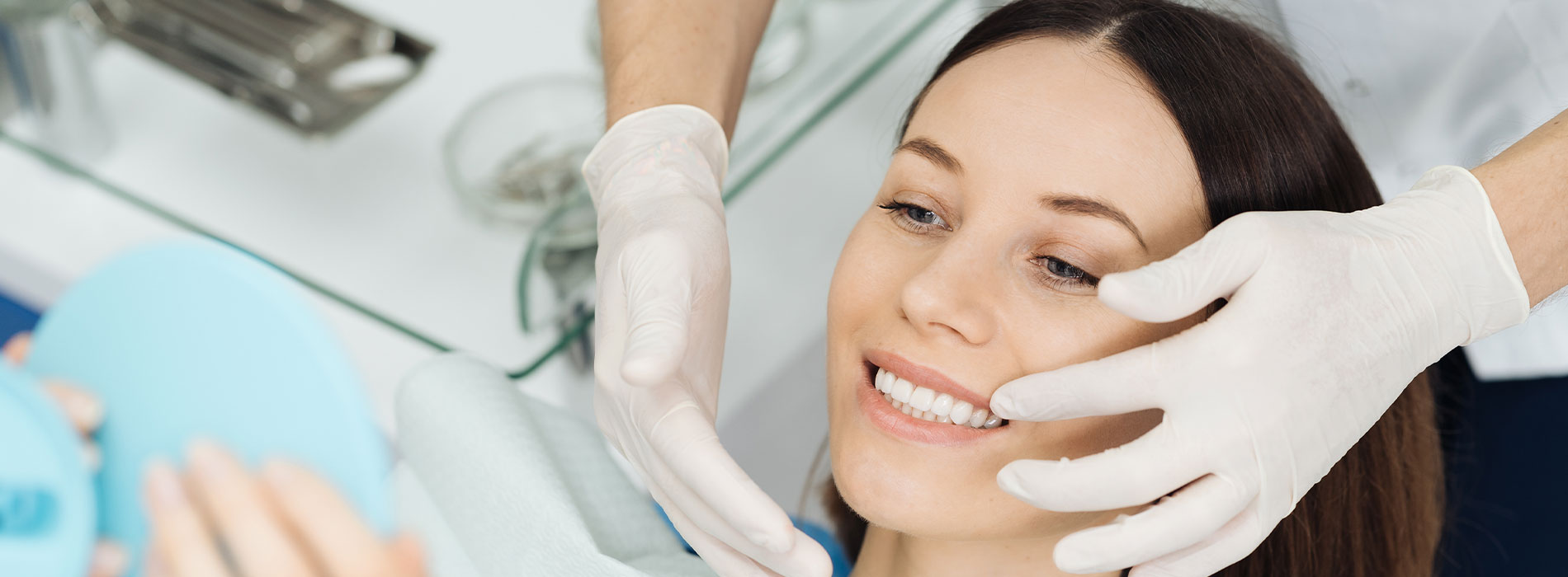A woman receiving a facial treatment with a face mask at a beauty salon, attended by a professional wearing gloves.