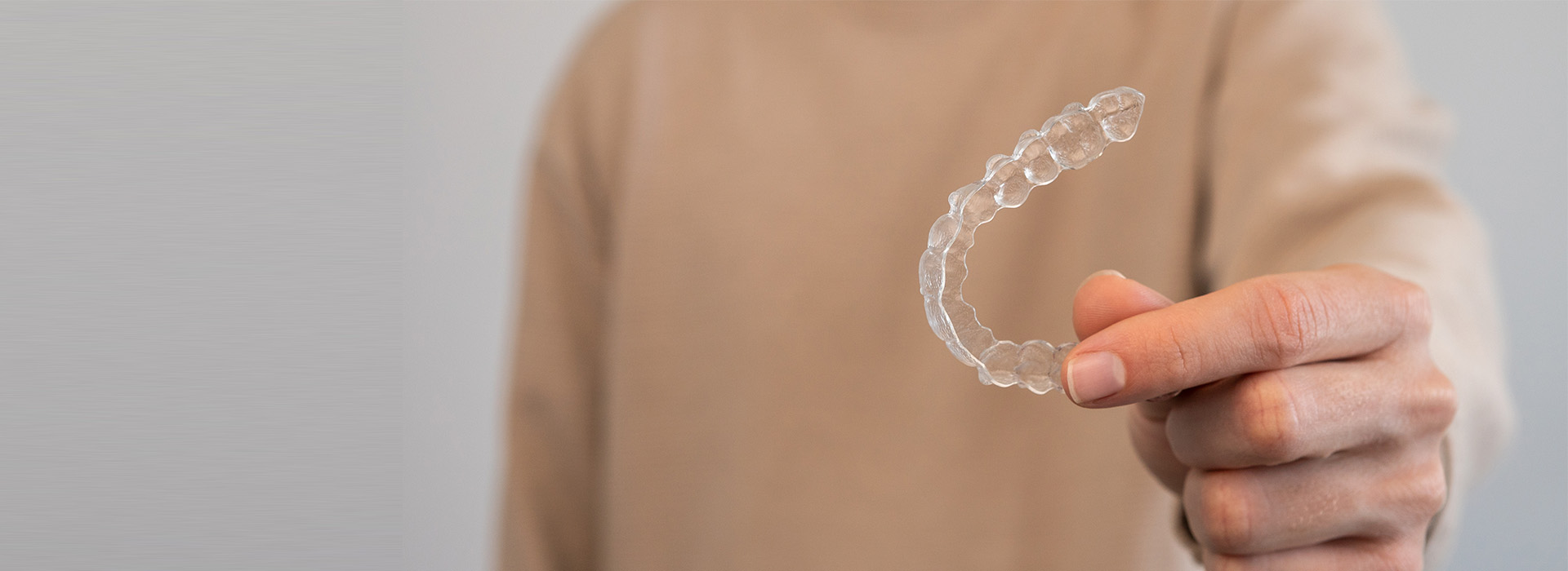 A person s hand holding a clear plastic ring with a water droplet shape.