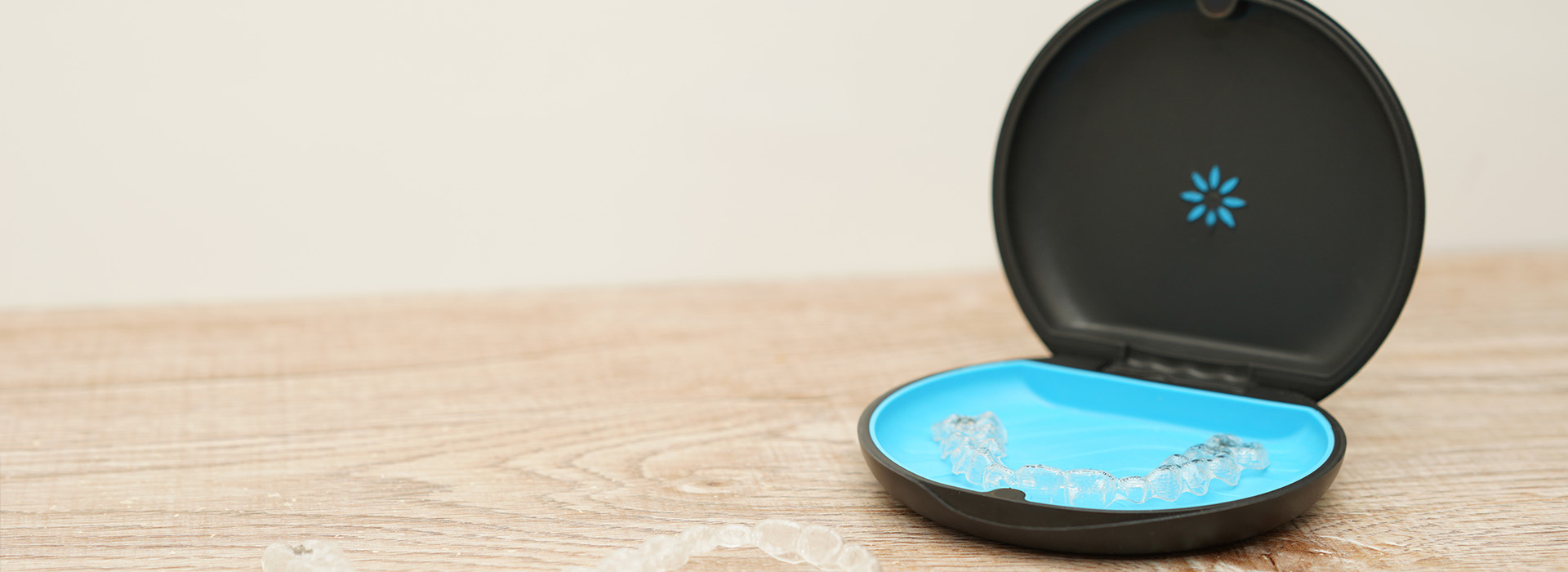 A small black electronic device with a blue circular object on top, placed on a white surface.