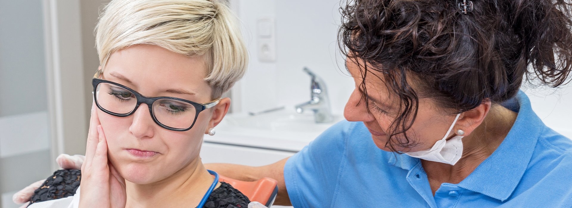 Woman with glasses being examined by dentist during dental appointment.