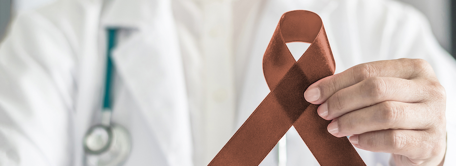 The image shows a medical professional holding a red ribbon, which is commonly associated with awareness campaigns for various causes, including breast cancer.