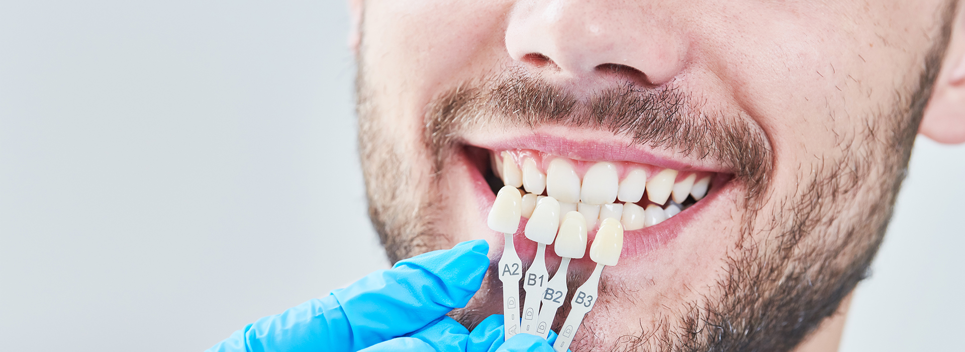Alt text  A smiling man with teeth being checked by dental tools in his mouth.