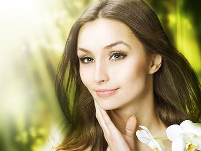 An attractive woman with blue eyes, wearing makeup, looking towards the camera with a serene expression.