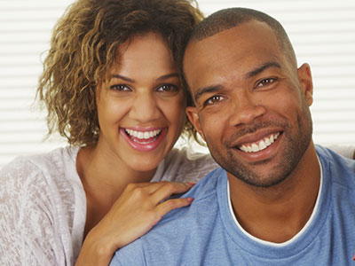 A man and woman are smiling at the camera, posing together with one arm around each other s shoulders.