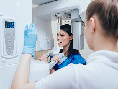 The image shows two individuals standing in front of a CT scan machine, with one person operating the device while another observes.