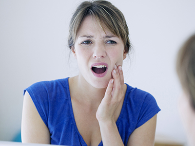 The image features a woman with her mouth open, displaying a toothbrush, and she appears to be speaking or singing, with an expression of surprise or concern on her face.