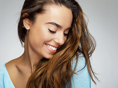 A woman with long hair smiles at the camera, capturing two expressions in a split-screen photo.