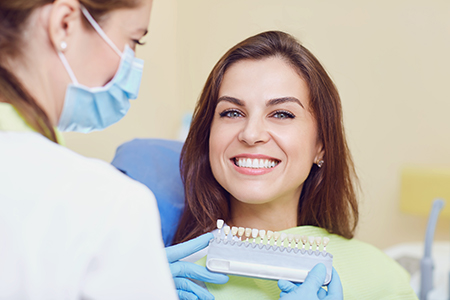 A woman sitting in a dental chair receiving a dental cleaning from a dentist.