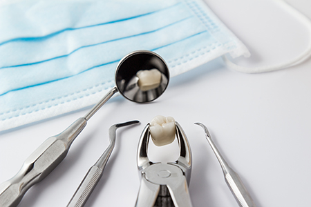 The image shows a collection of dental tools, including a toothbrush and several pairs of scissors, placed on a white surface next to a blue cloth with a hole for holding instruments.