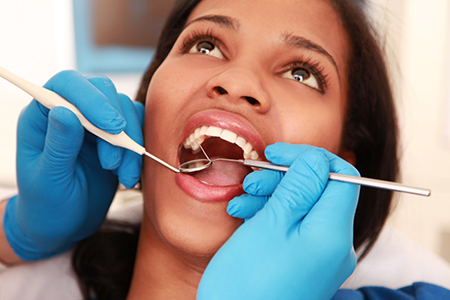A woman receiving dental care with a hygienist using tools.