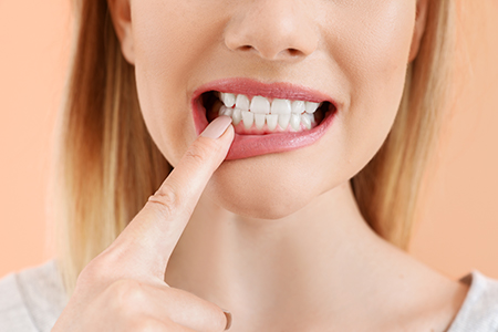 A woman with her finger on her mouth, looking directly at the camera, with a neutral expression.