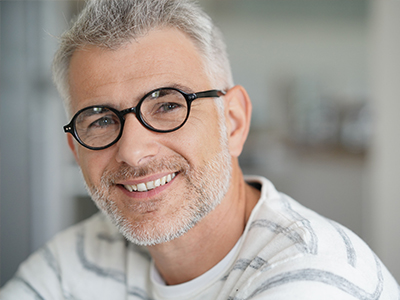 The image shows a man with glasses smiling at the camera, with two different images of him on either side, suggesting a before-and-after comparison or a transformation theme.