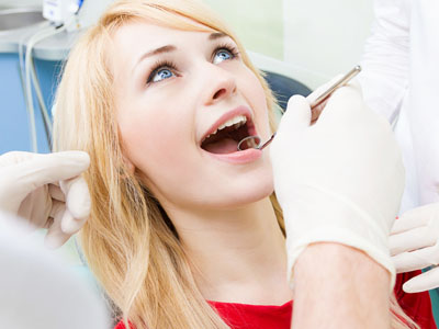 The image depicts a person receiving dental treatment, with a dentist performing a procedure on their teeth while they are seated in a dental chair.
