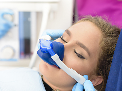 Woman receiving medical treatment with oxygen mask on her face.