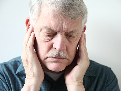 The image shows two photographs of an elderly man with his hand on his face, appearing distressed or pained.